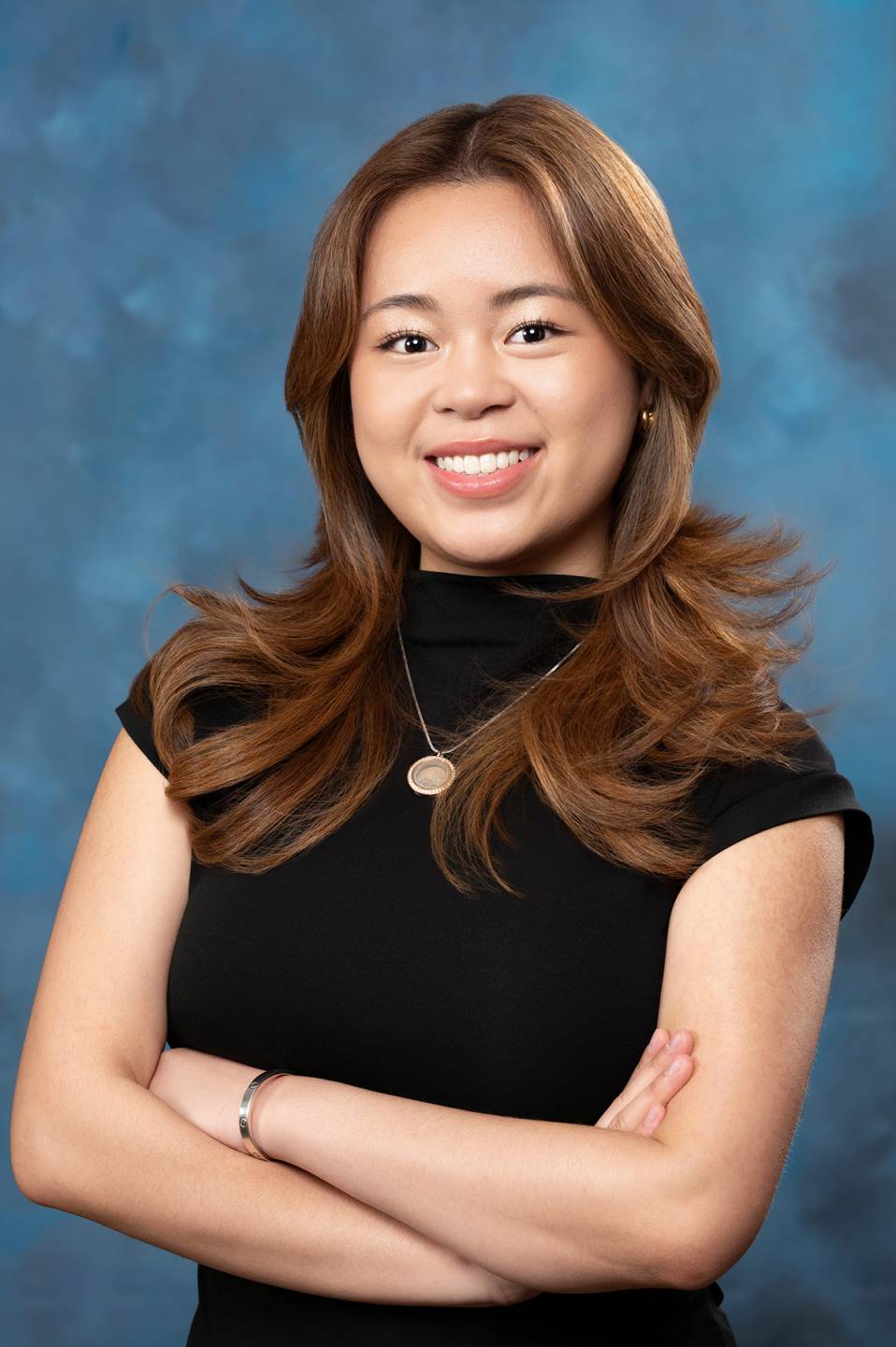 asian brunette with arms crossed wearing black blouse with gold necklace