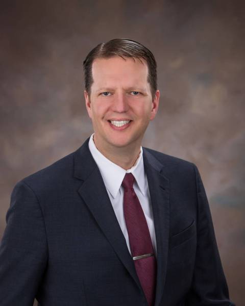 male with navy blazer, white collared shirt and burgundy neck tie.